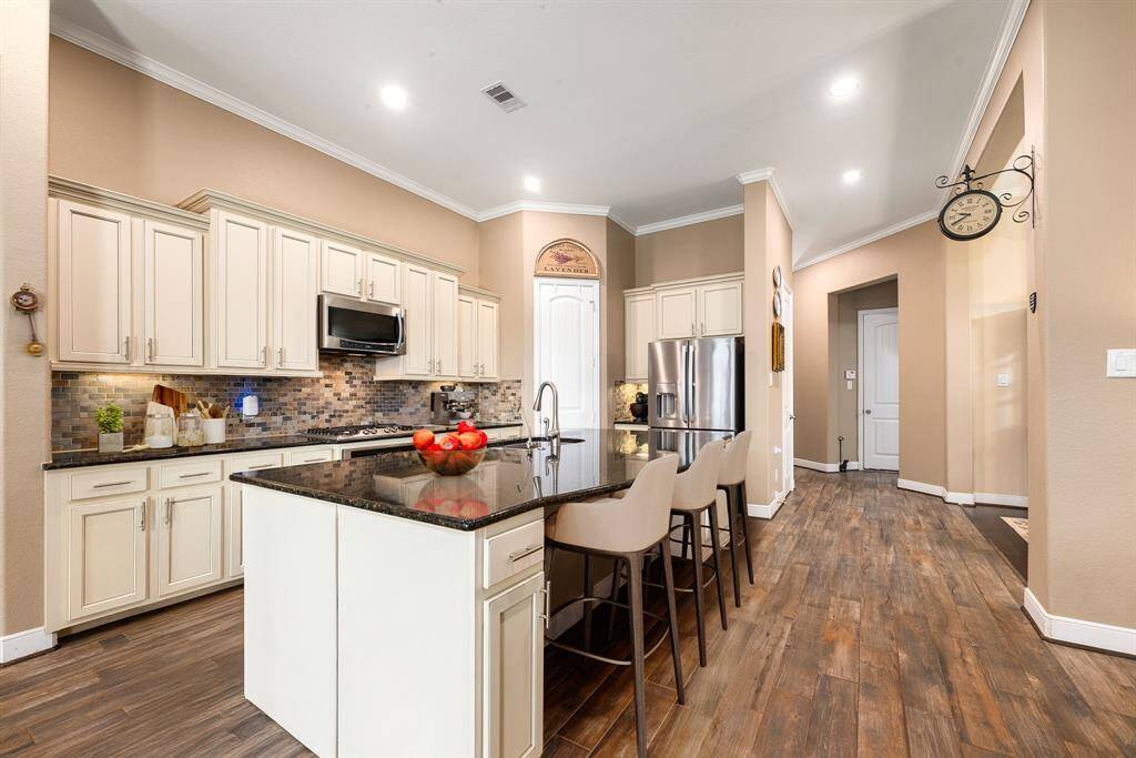 This stunning kitchen displays such a beautiful contrast with the light cabinets, custom neutral paint, granite countertops, modern backsplash, SS appliances, large kitchen island with extra storage, breakfast bar, recessed lighting and walk in pantry. *virtual staging*