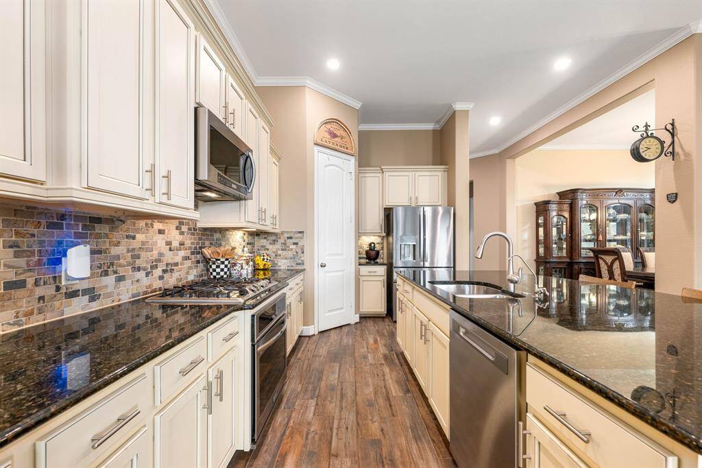 This stunning kitchen displays such a beautiful contrast with the light cabinets, custom neutral paint, granite countertops, unique tile backsplash, SS appliances, oversized kitchen island with extra storage, breakfast bar, recessed lighting, crown molding and walk in pantry.