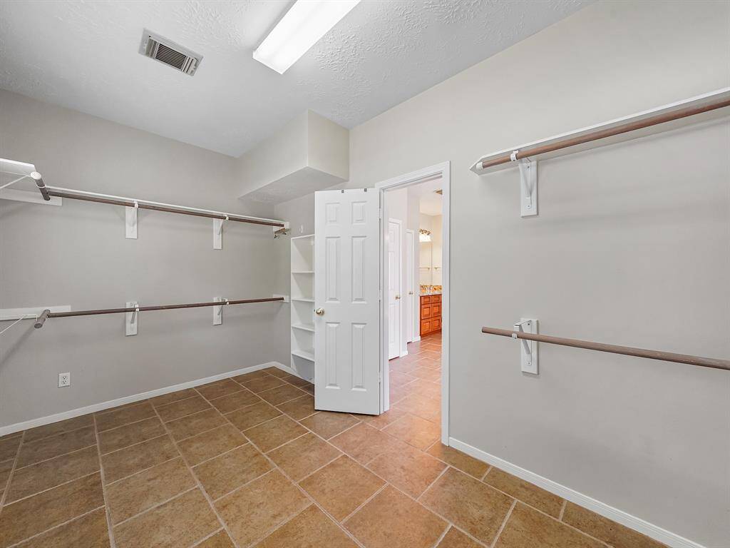 Spacious primary retreat walk-in closet with multi-level hanging racks and shelving.