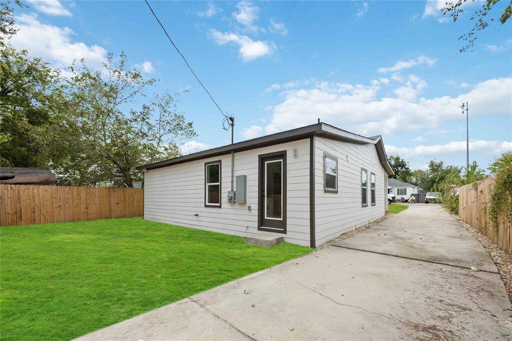 The backyard of the single-story home with a long concrete driveway that leads to the back.