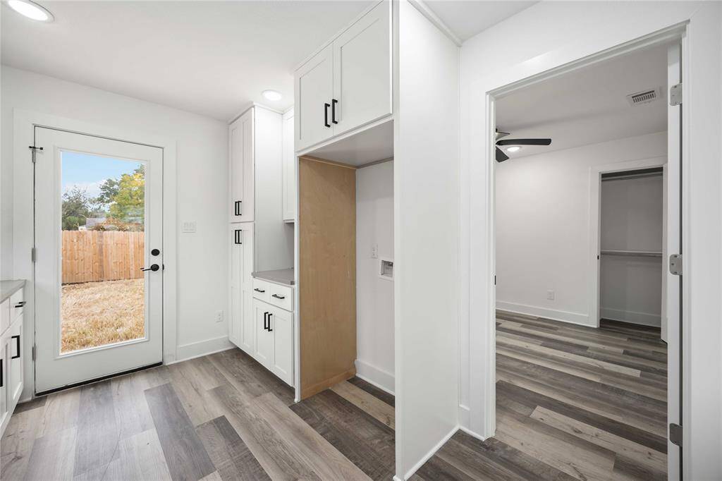Contemporary finishes in the kitchen with polished white cabinetry and direct access to a fenced backyard through a glass door.