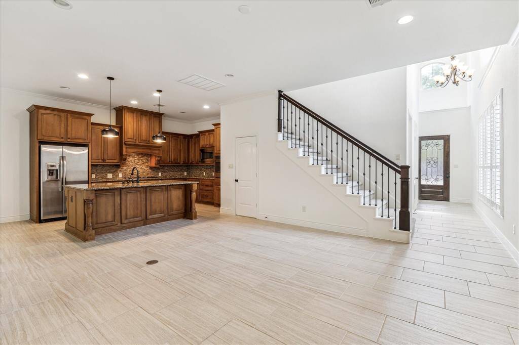 Open-concept with soaring ceilings, recessed lighting, and a statement staircase. Chef’s kitchen features custom cabinetry, granite counters, and designer lighting—perfect for entertaining."
