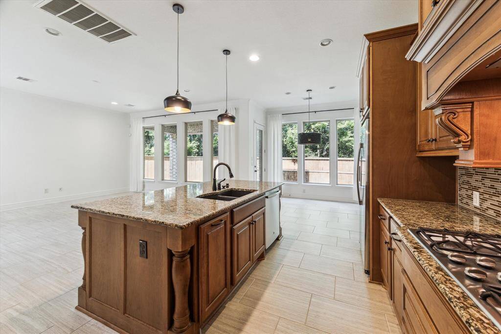 Light-filled and open, this kitchen seamlessly blends luxury and function—granite counters, custom cabinetry, and panoramic backyard views make it the heart of the home.