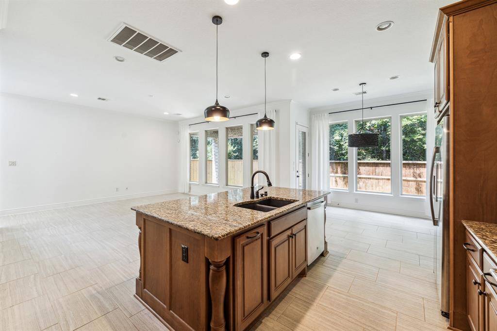 This tasteful kitchen features a large granite island with stylish pendant lighting, opening to a bright breakfast room and spacious living area—all with beautiful views of the backyard.