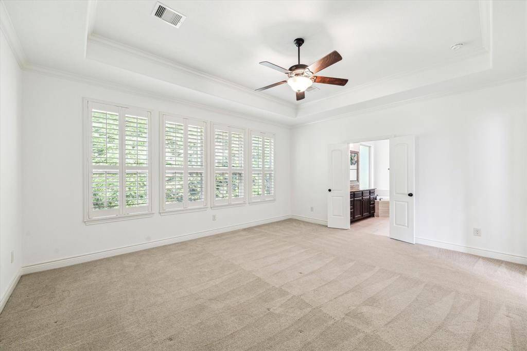 Expansive primary suite featuring plush neutral carpet, classic plantation shutters, and direct access to the luxurious en-suite bath.