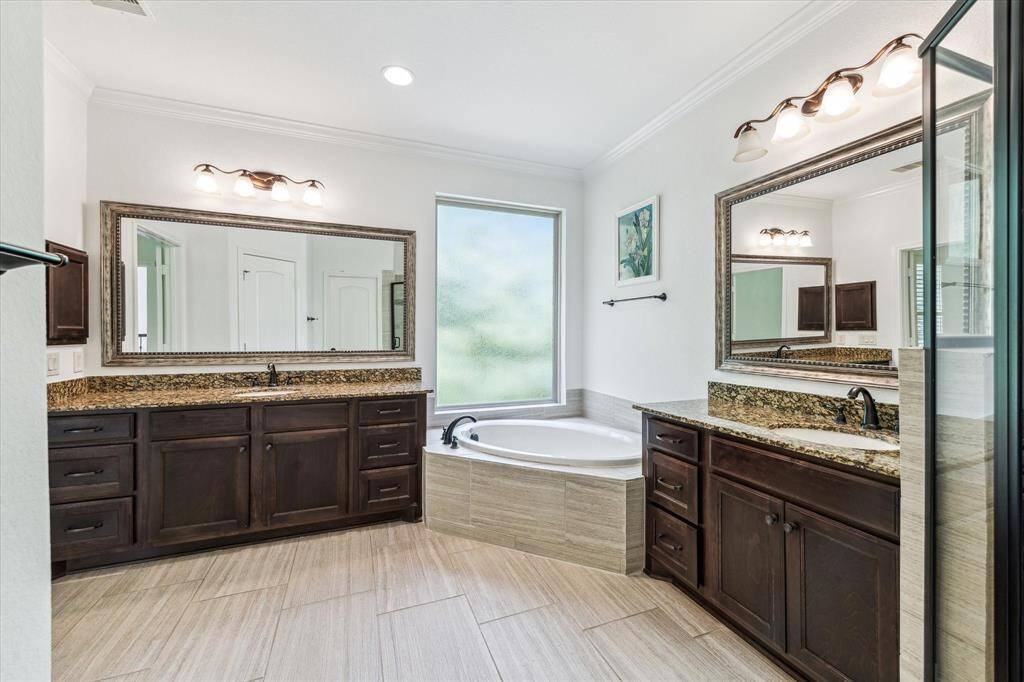 Spa-inspired primary bath featuring rich espresso cabinetry, granite counters, dual vanities, a sunlit soaking tub, and a spacious walk-in shower—your private retreat awaits.