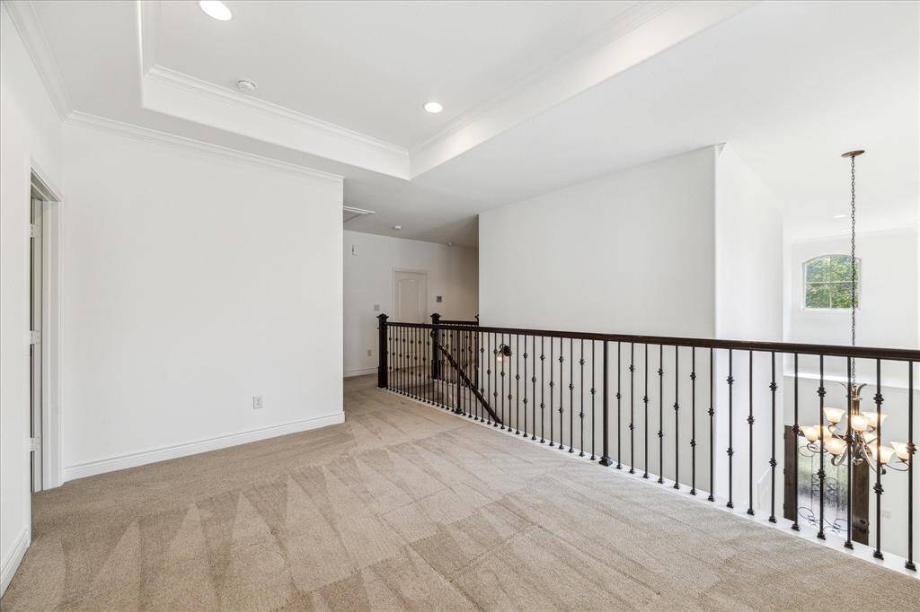 Upstairs den with tray ceiling, recessed lighting, and wrought iron railing overlooking the foyer.