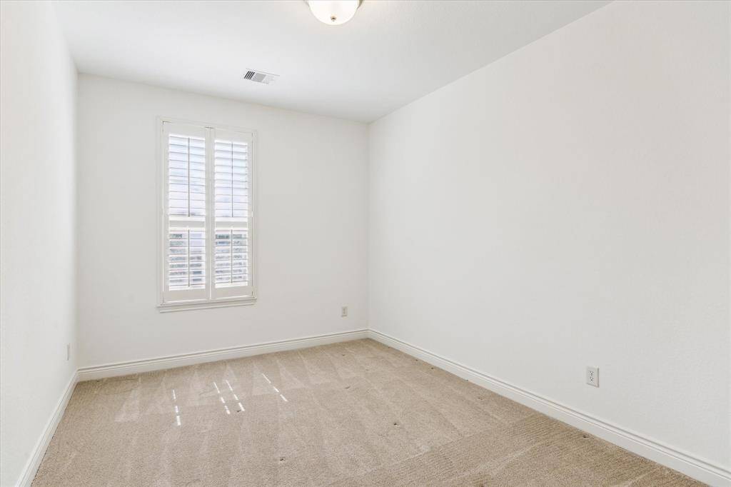 Bright secondary bedroom with plantation shutters and neutral carpet.