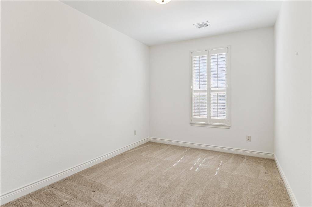 Cozy secondary bedroom with plantation shutters and plush neutral carpet.