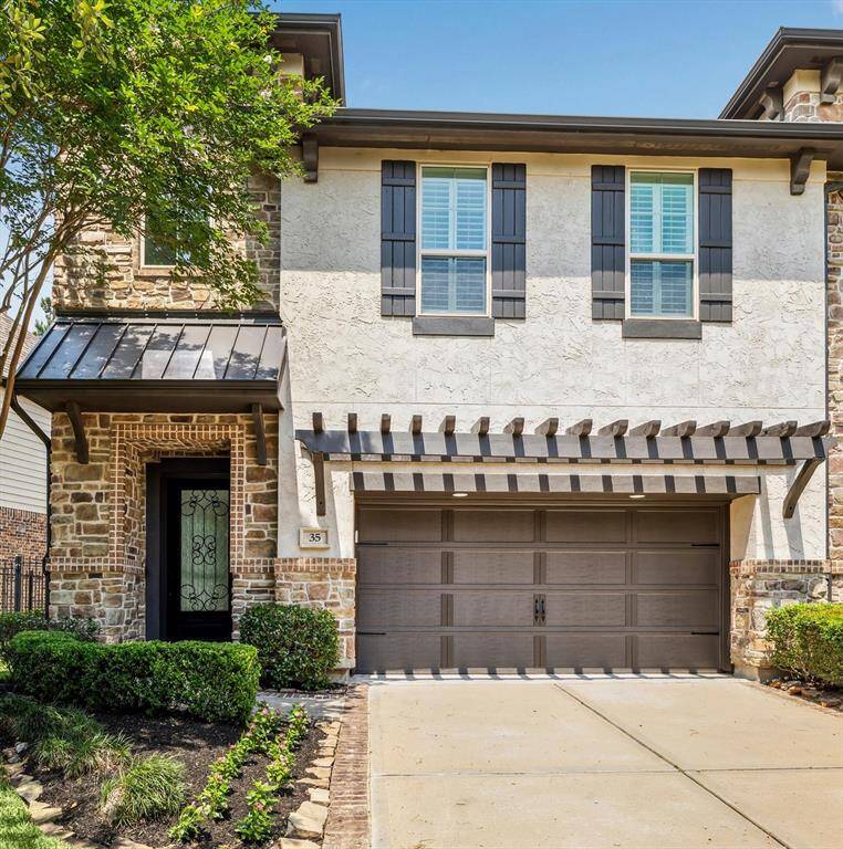 Sophisticated two-story home with stone and stucco exterior, designer shutters, and a sleek pergola over the modern double garage. Finished with a wrought-iron entry and manicured landscaping.