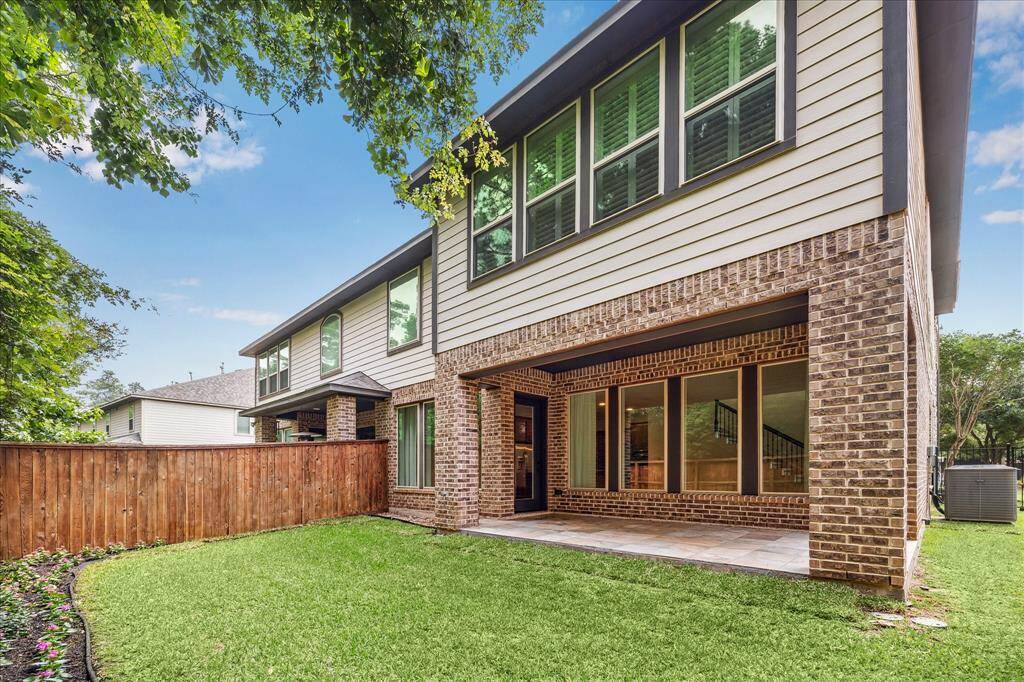 Chic and serene, this private backyard oasis features a stylish covered patio, lush greenery, and modern brick charm—perfect for unwinding or entertaining in style.