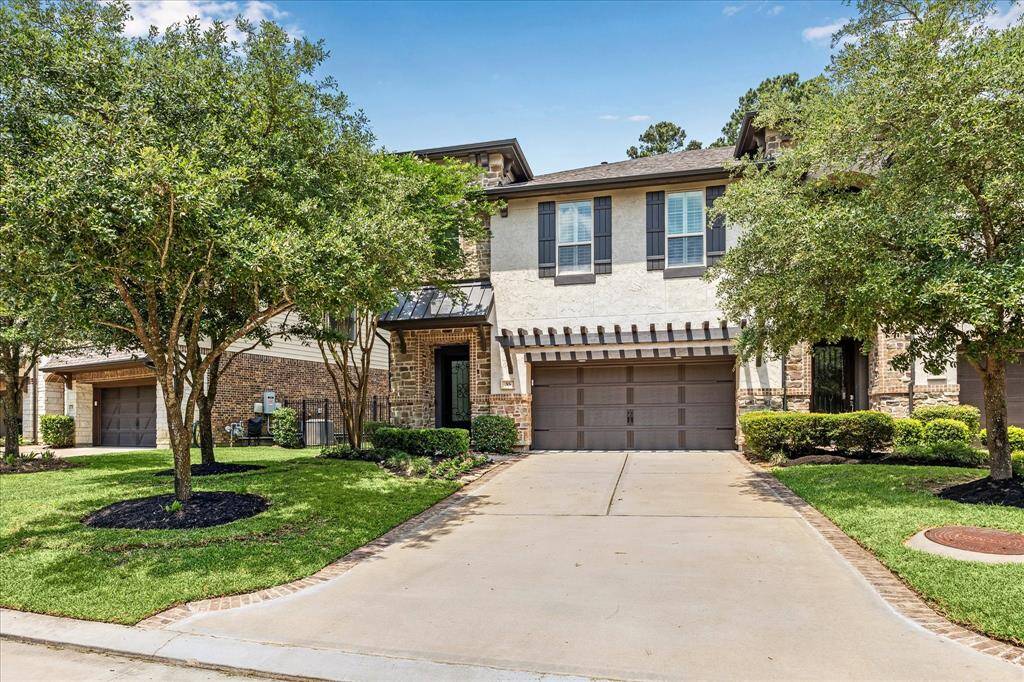Stunning two-story townhome with a stone and stucco exterior, modern shutters, and a pergola-accented garage. Nestled on a tree-lined lot with pristine landscaping and great curb appeal.
