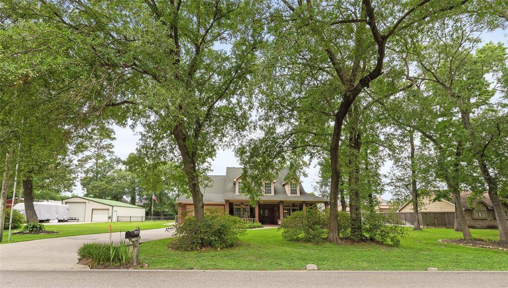 Home is set back from the road, surrounded by mature trees and lush greenery. It features a welcoming front porch and a long driveway leading to attached garage are perfect for those seeking privacy and a serene, park-like setting.