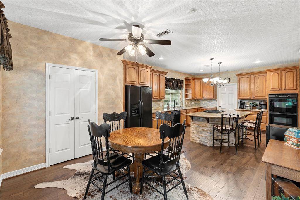 The kitchen/breakfast room is well-lit with ceiling fixtures and a fan, and boasts a cozy, inviting atmosphere with a touch of rustic charm.