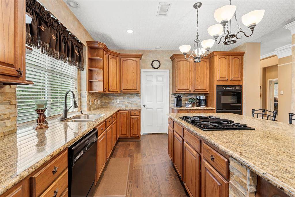 This kitchen offers ample storage, a double sink under large windows, and elegant lighting fixtures, creating a bright and functional space.