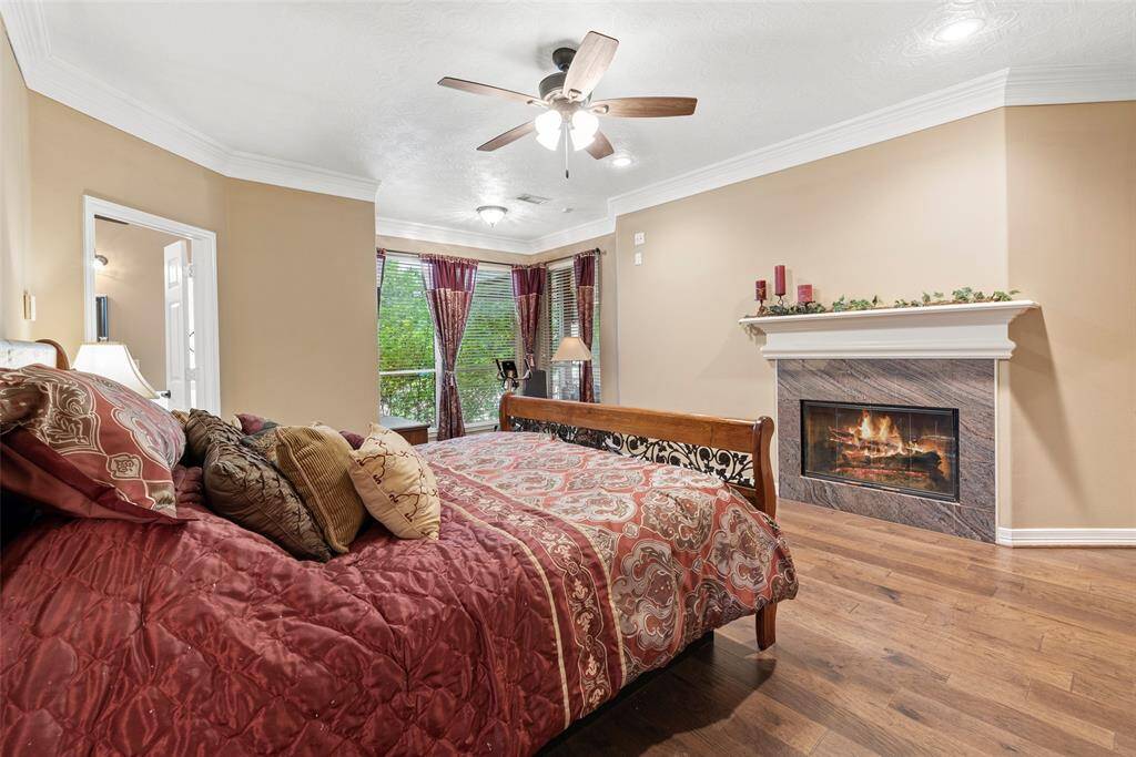 Elegant crown molding and wood flooring add a touch of sophistication to primary bedroom.