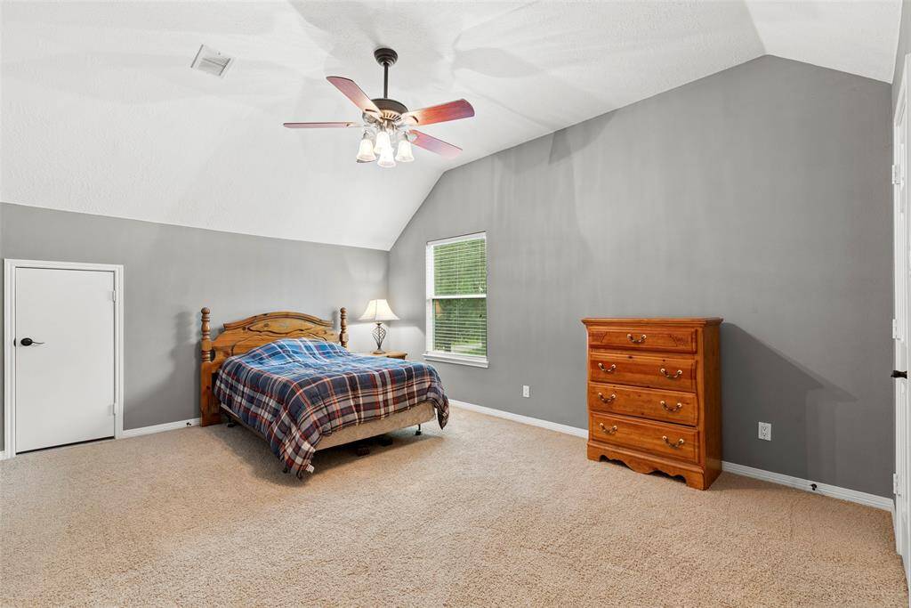Secondary bedroom features neutral gray walls, carpeted flooring, and a ceiling fan. Room offers direct access to bathroom.