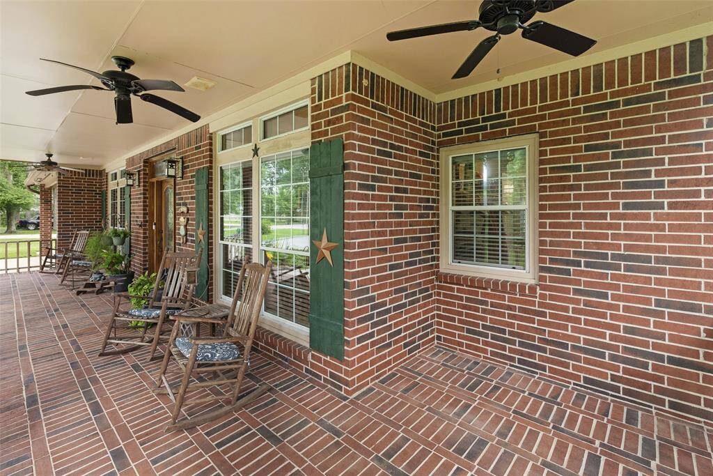 Charming brick front porch with ceiling fans, rocking chairs, and decorative shutters, perfect for relaxing and enjoying the outdoors.