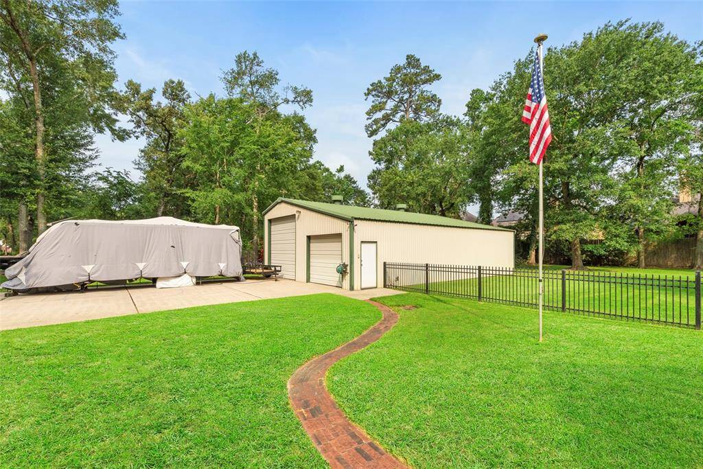 Almost an acre of lush grass, featuring a large metal shed, a neatly covered area for storage, and a flagpole. Surrounded by mature trees, offering privacy and a serene atmosphere.