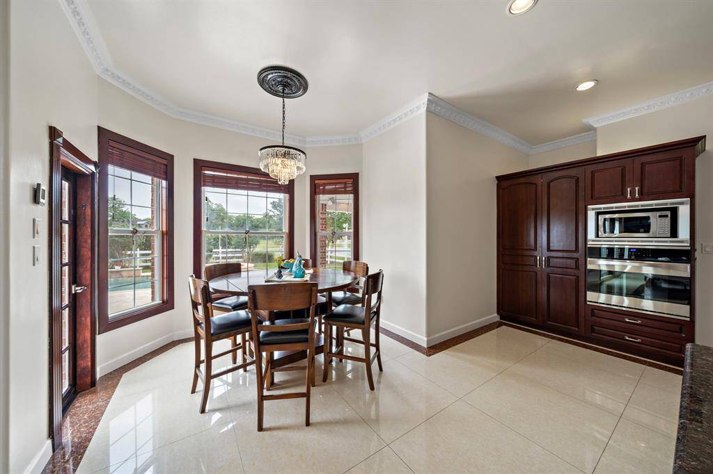To the left of the oven/microwave is a large pantry cabinet. The door to the left of the breakfast table leads to the back patio.