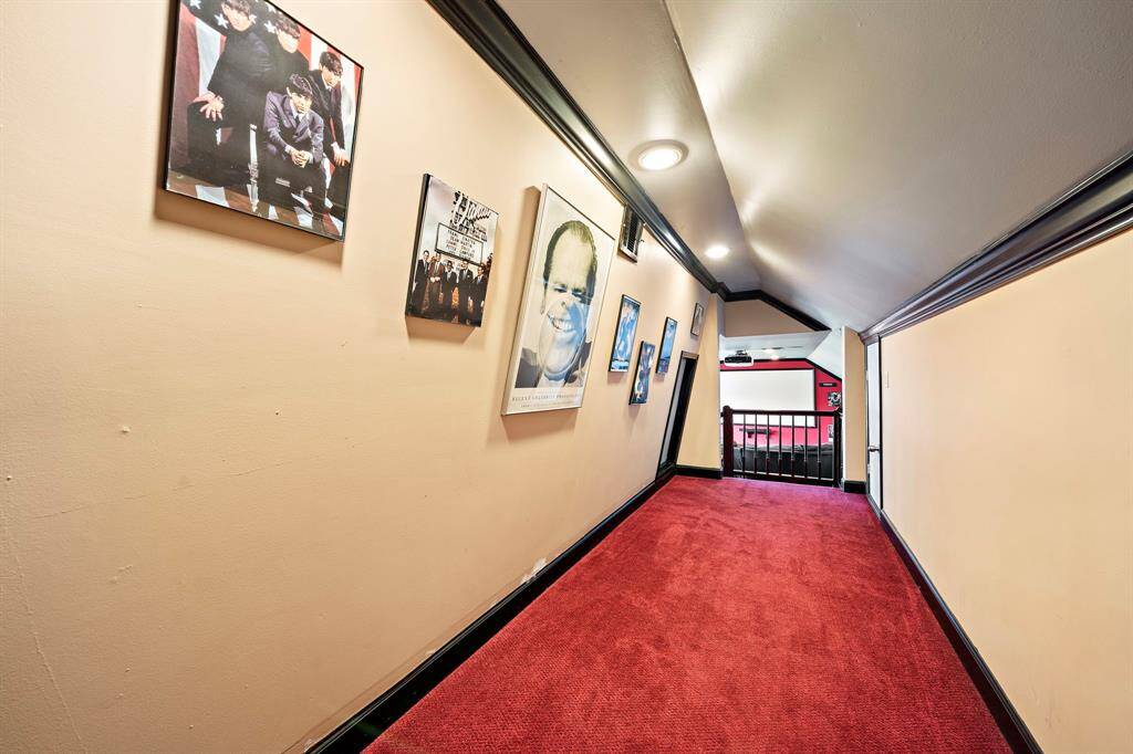 The corridor leading to the media room has movie posters. The wall is slanted on one side. Attic access is behind the half doors.