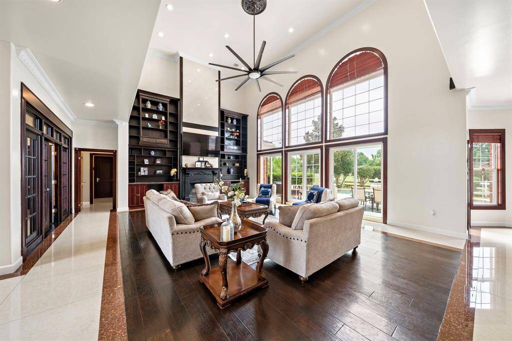 A gas log fireplace is surrounded by dramatic soaring built-ins. The floors are a mixture of inlay marble tile and granite with inset hardwoods.