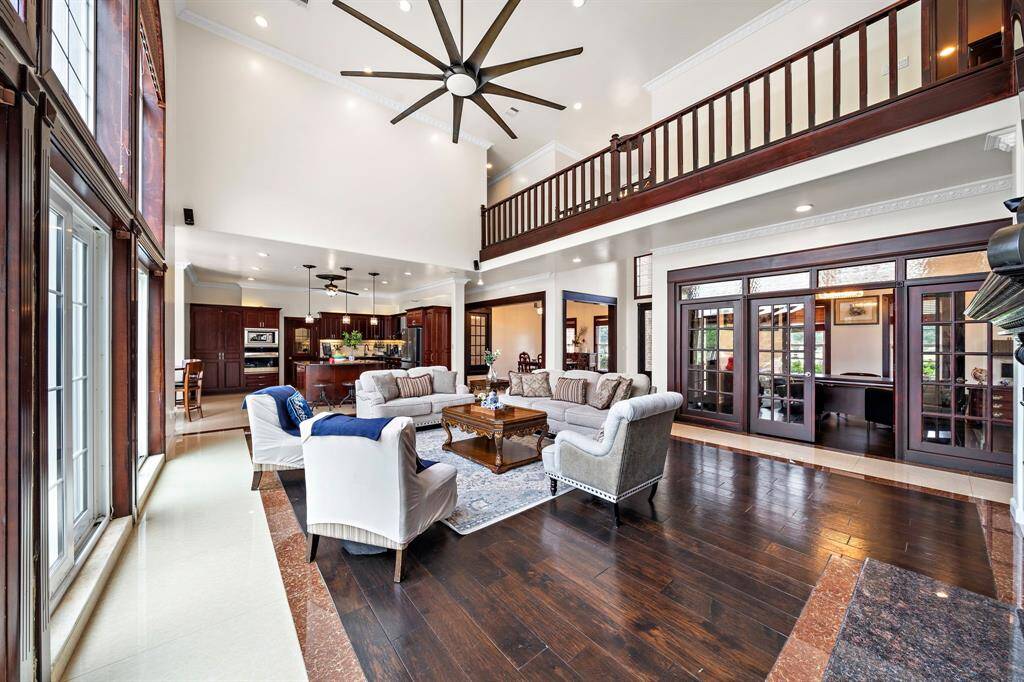 The second floor walkway spans the living room. An office/study is enclosed with glass doors.