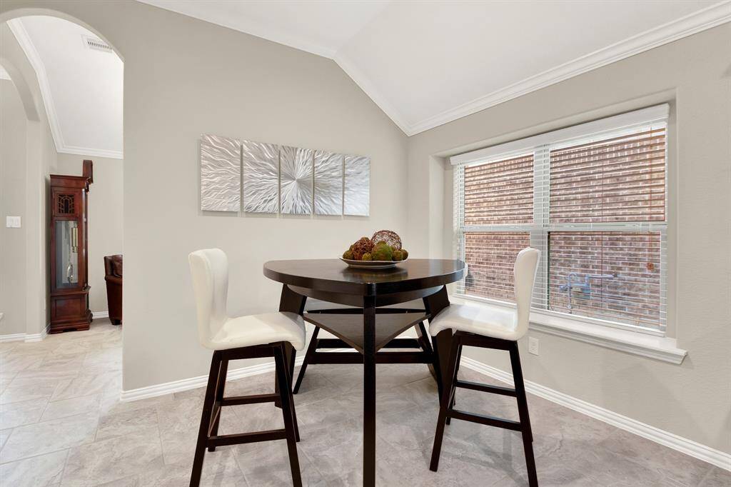 This cozy dining nook features a stylish round table with two modern chairs, set against neutral walls and large windows that provide ample natural light. The space is perfect for casual meals or coffee breaks.
