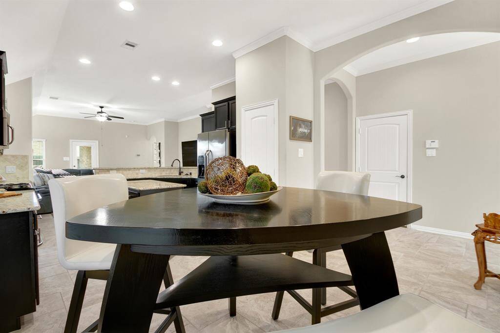 Bright and open kitchen and dining area with modern finishes, high ceilings, and a view into the living space. Features a sleek dark wood table and light cabinetry, creating a welcoming ambiance.