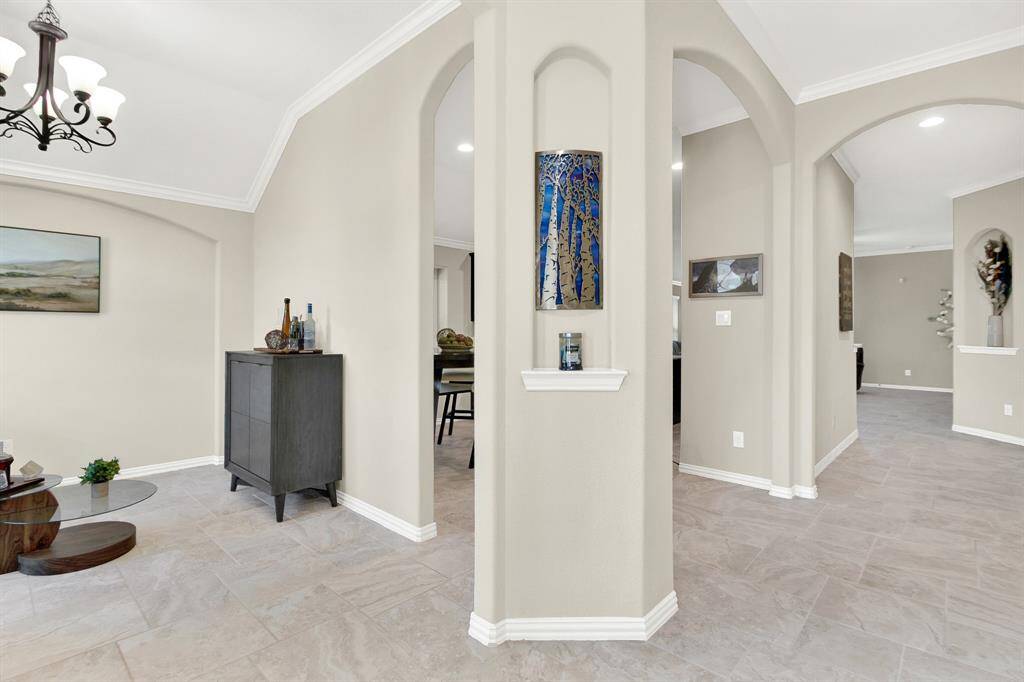 This photo showcases a modern interior with neutral tones, featuring elegant archways and tile flooring. The space includes decorative wall niches and contemporary light fixtures, offering a welcoming and spacious feel.