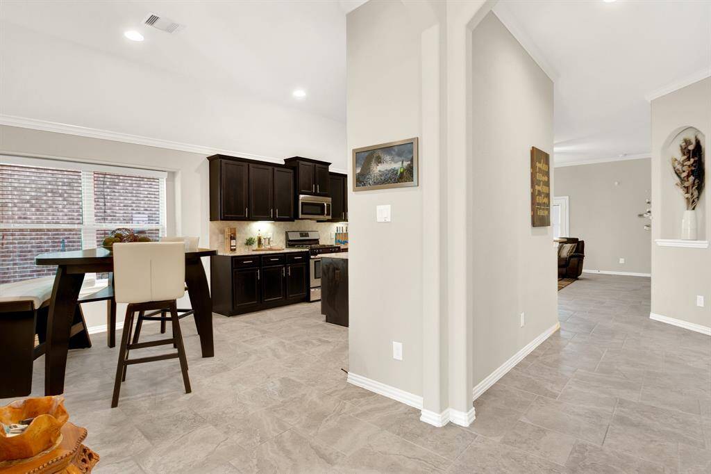 This photo showcases a modern open-concept interior with a spacious kitchen featuring dark cabinetry, stainless steel appliances, and a dining area with ample natural light. The adjacent living space has a neutral color palette, offering a clean and inviting atmosphere.