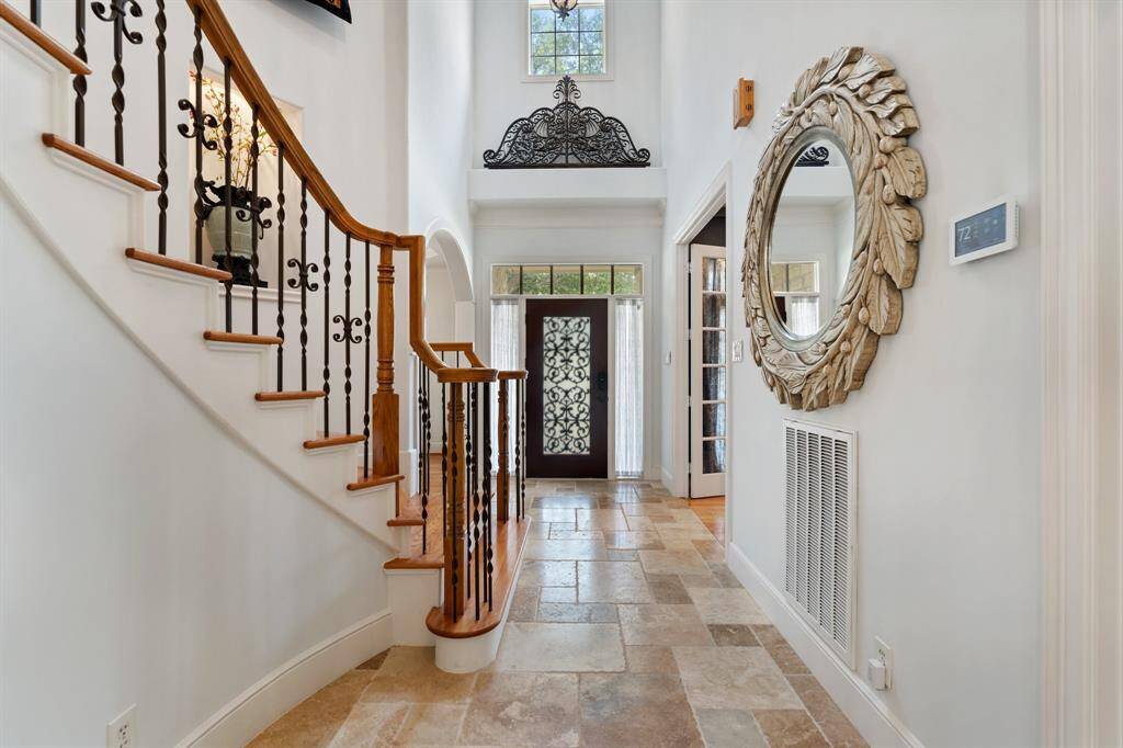 The grand entryway showcases soaring double-height ceilings, elegant hanging light fixtures, and a sweeping staircase—making a striking first impression.