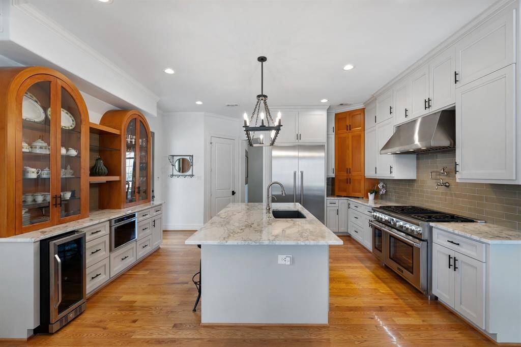The kitchen features sleek marble countertops, a large center island, Thermador stainless steel appliances, and custom-built cabinetry.