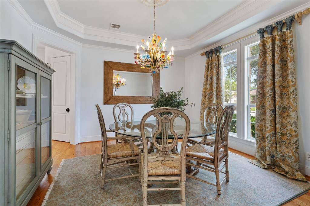 The formal dining room features elegant crown molding, oversized windows for natural light, and seamless access to both the kitchen and entry.
