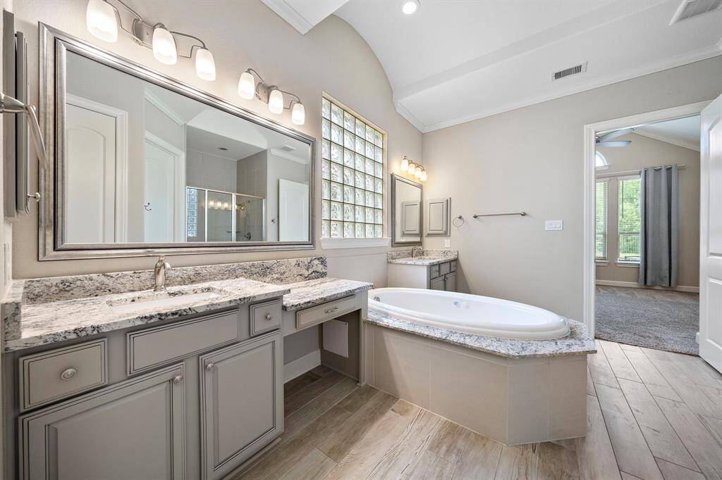 Primary bathroom features double sinks, a jetted soaking tub, and a vanity sitting area.