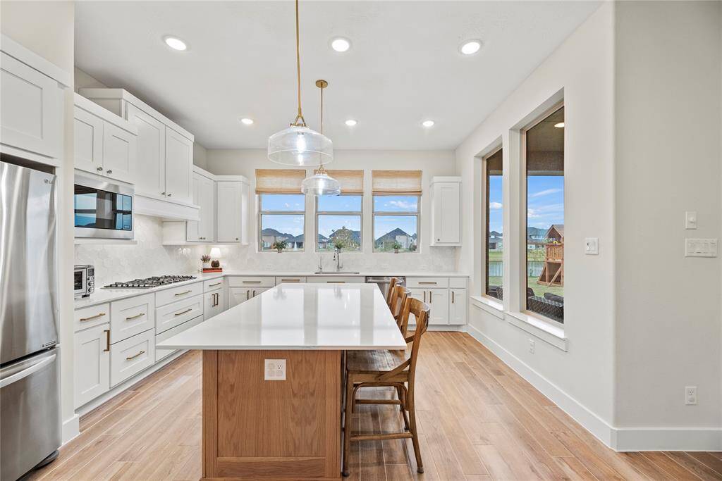The sprawling island with breakfast bar seating serves as a versatile centerpiece, providing additional workspace, storage, and seating for casual dining or entertaining.