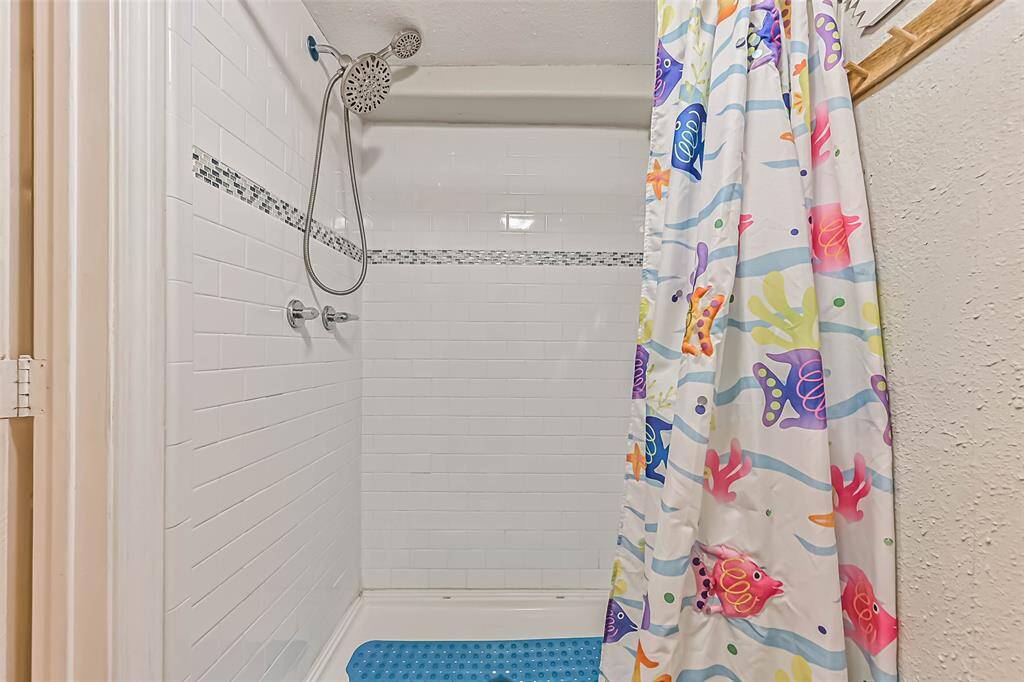Ground level restroom with walk in shower surrounded by subway and accent tile