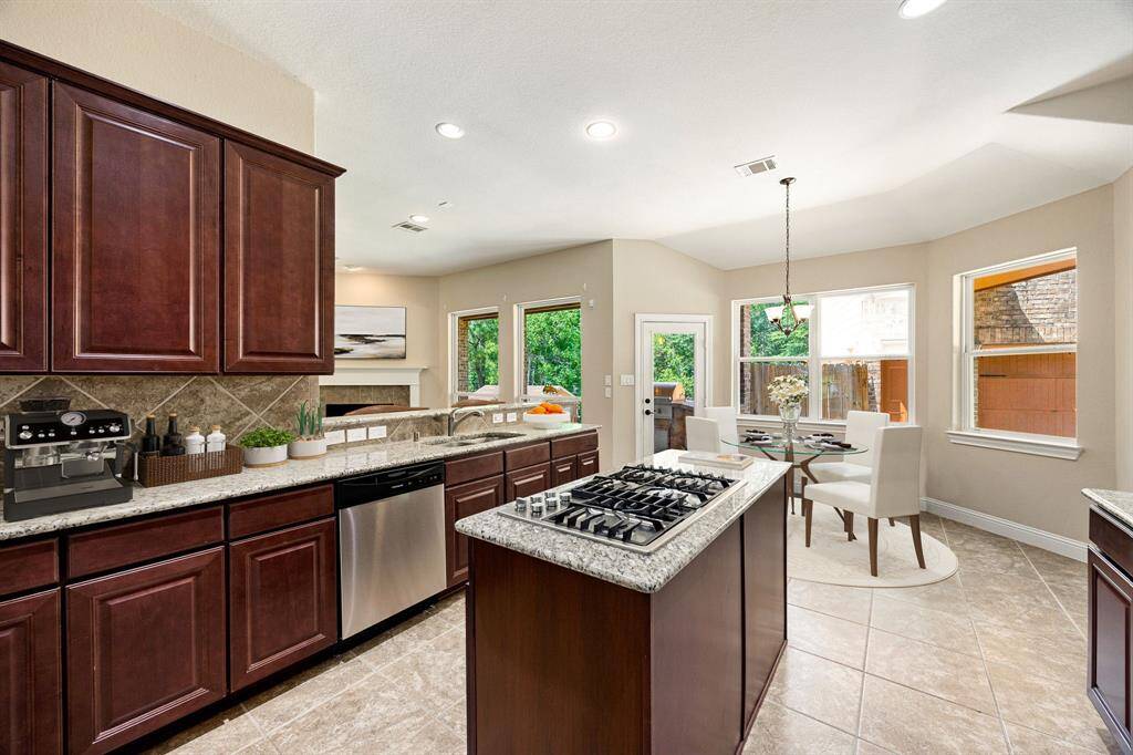 This stunning kitchen displays such a beautiful contrast with the dark stained cabinets, custom neutral paint, granite countertops, light modern backsplash, and SS appliances, oversized kitchen island with extra storage, breakfast bar, recessed lighting, high ceilings and walk in pantry.