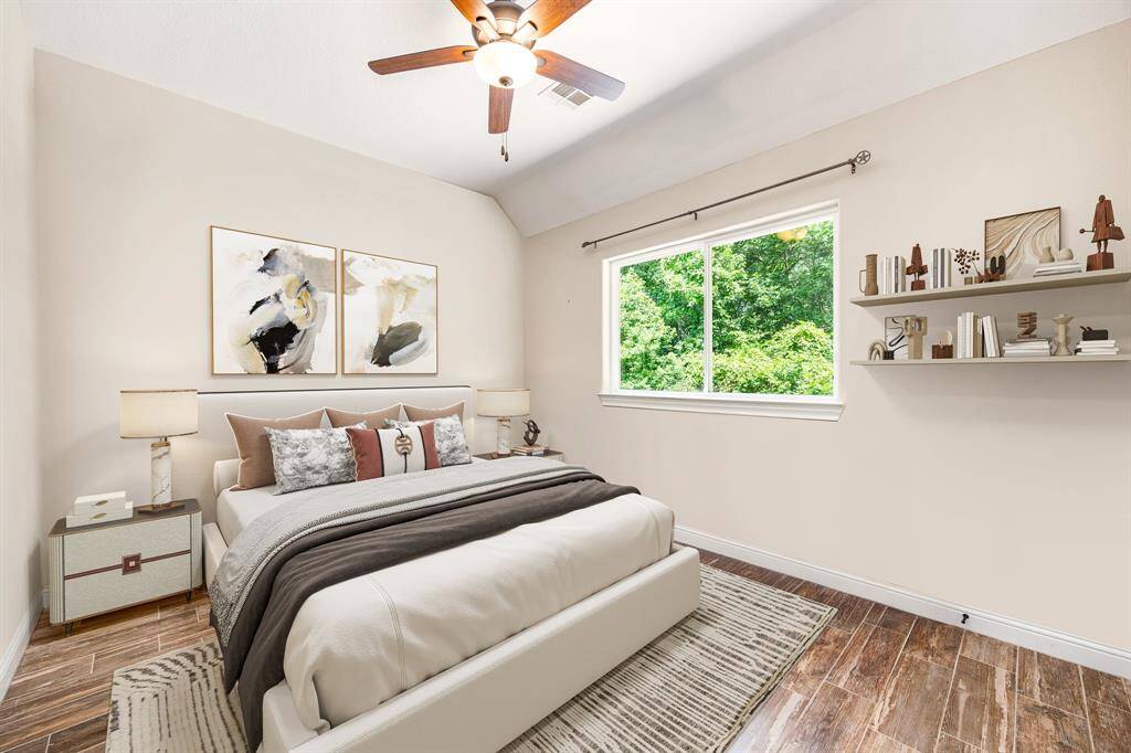 Secondary bedroom features wood style flooring, custom paint, dark stained ceiling fan with lighting and a large window with privacy blinds. *Virtually Staged