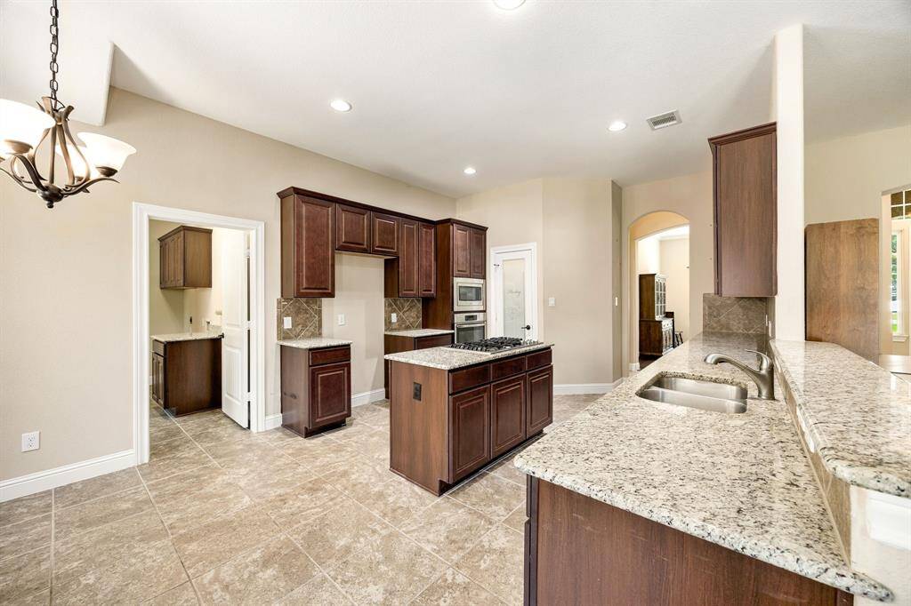 This kitchen is by far any chef’s dream! This spacious kitchen features dark stained wood cabinets, granite countertops, SS appliances, modern tile backsplash, recessed lighting with extended counter space, granite kitchen island with double sink and space for breakfast bar and a walk-in pantry all overlooking your huge family room.