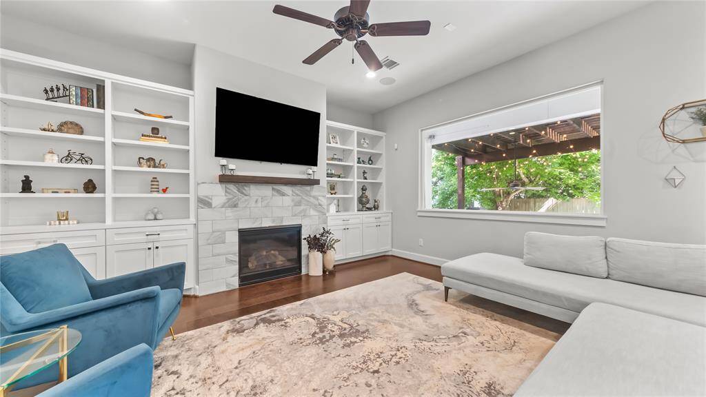 The living room offers a cozy atmosphere with a the elegance of a fireplace and custom built shelves and storage.