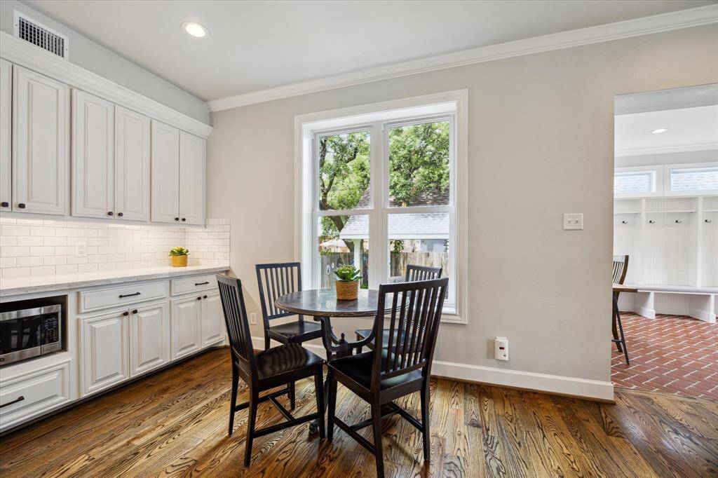 Framed by a picturesque window, the cozy breakfast area seamlessly connects to the charming mudroom, all set against a backdrop of custom cabinetry and warm hardwood floors.