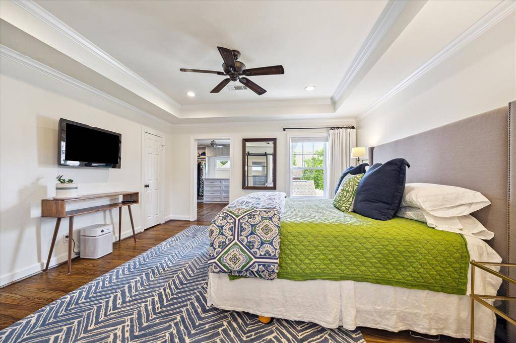 An additional view of the primary suite reveals a spacious layout with crown molding, recessed lighting, and direct access to a custom walk-in closet illuminated by natural light.