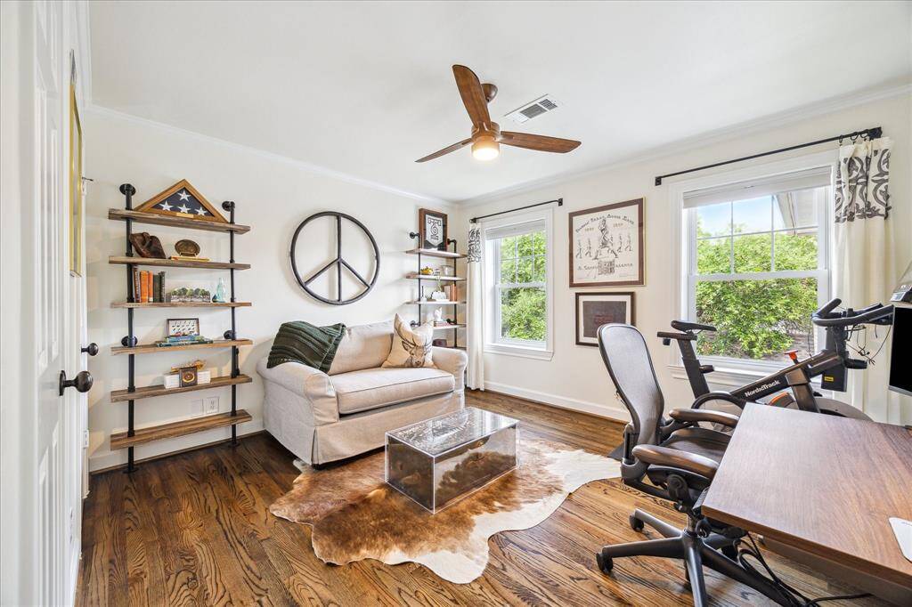 This light-filled home office offers a stylish and functional retreat with warm hardwood floors, custom shelving, and serene views framed by oversized windows.