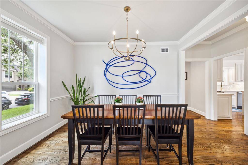 The formal dining room offers a sophisticated setting for entertaining, featuring rich hardwood floors, elegant millwork, and contemporary art that adds a bold, modern touch.