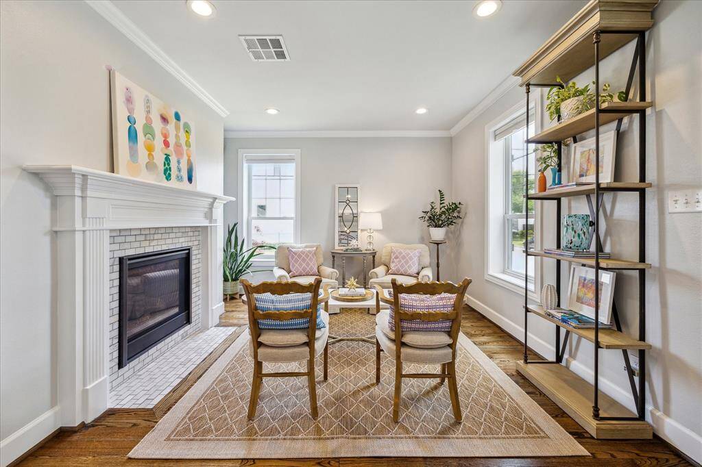 This inviting living space features a classic fireplace with timeless millwork, abundant natural light, and thoughtfully curated furnishings that create a warm and elegant atmosphere.
