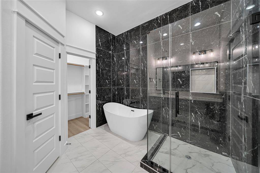 Master bathroom features a double vanity with sleek gray cabinets, marble countertops, and elegant black fixtures.