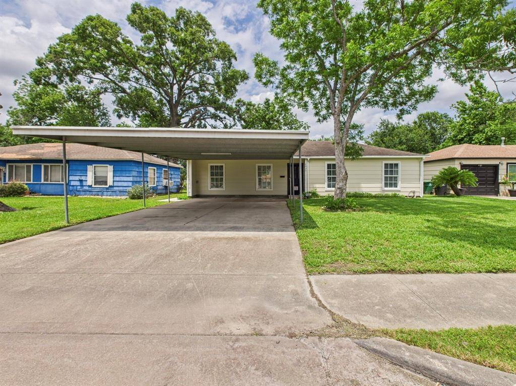 A cozy single-story home with a spacious carport and driveway, set in a lush yard with mature trees. Is situated in a quiet neighborhood, offering a welcoming and serene environment.