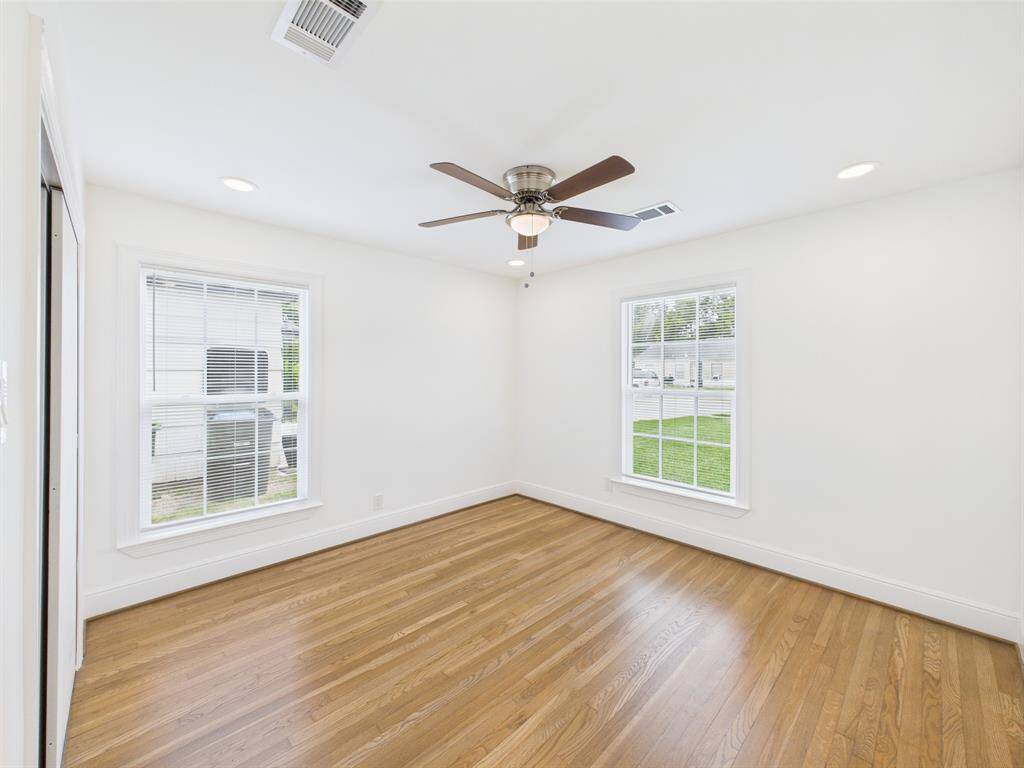 Second bedroom with hardwood flooring, two large windows for natural light, and a ceiling fan for comfort. Ideal for a bedroom or office.