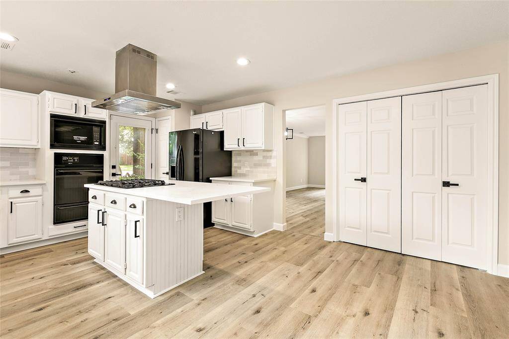 Bright and inviting kitchen area with plenty of storage options and contemporary finishes, highlighting a neatly tucked-away laundry space with washer and dryer behind closed doors for a polished and uncluttered appearance.